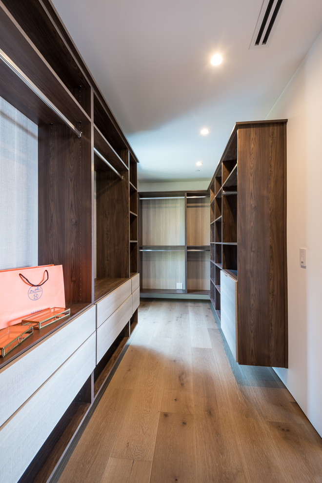 Large contemporary men's dressing room in Los Angeles with flat-panel cabinets, medium wood cabinets, medium hardwood floors and brown floor.