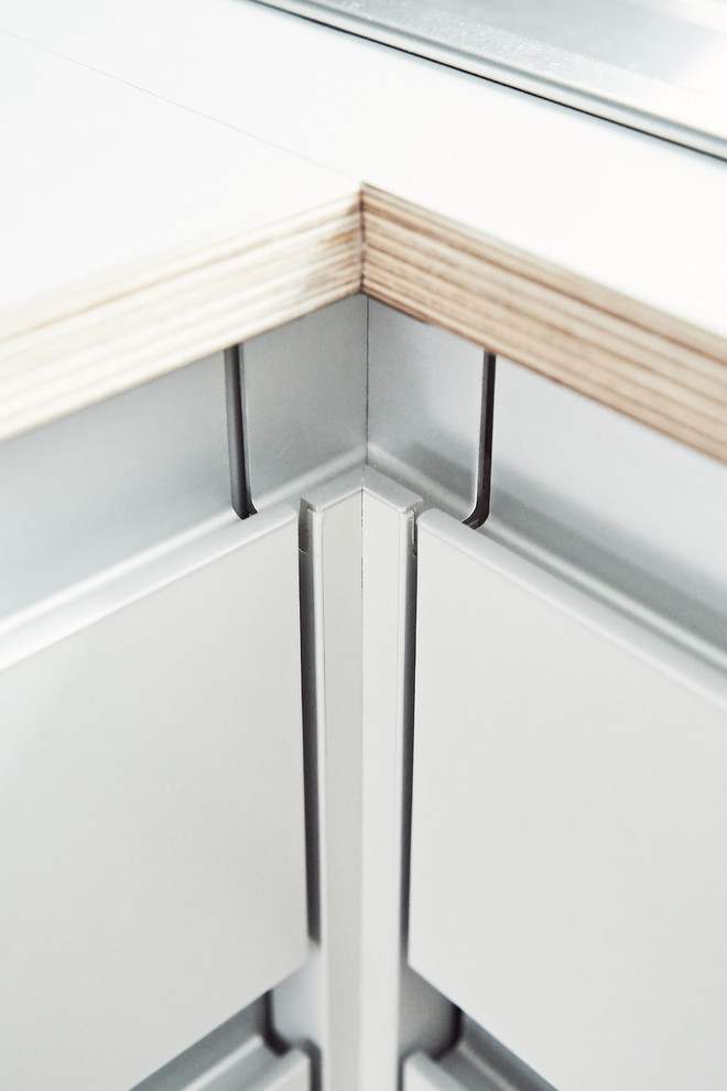 Kleine Moderne Wohnküche in L-Form mit Einbauwaschbecken, flächenbündigen Schrankfronten, grauen Schränken, Küchenrückwand in Grau, Küchengeräten aus Edelstahl und grauer Arbeitsplatte in München