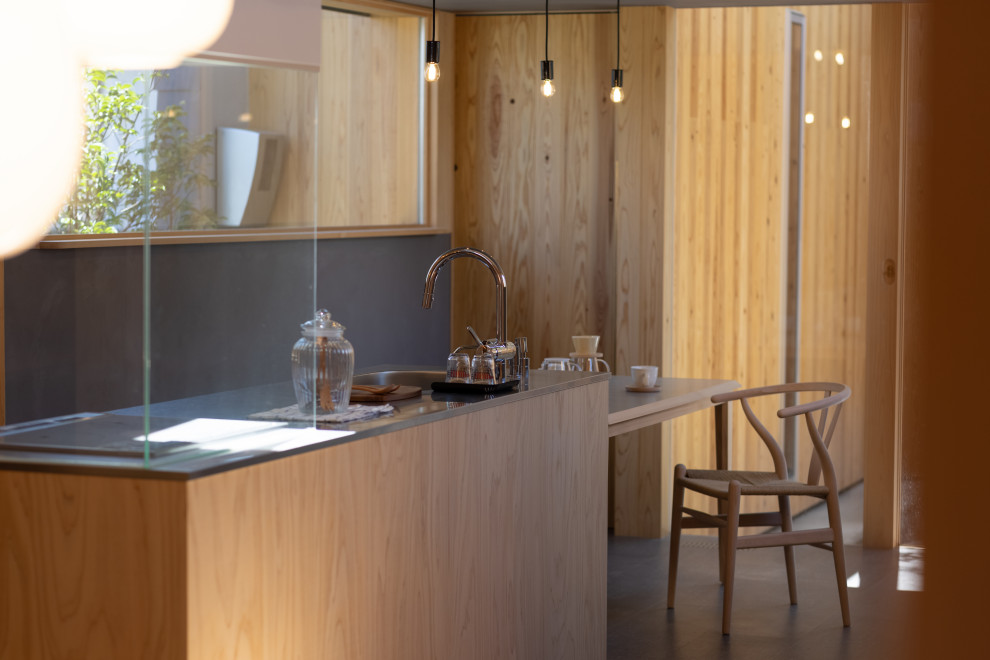 Idee per una cucina moderna di medie dimensioni con lavello sottopiano, ante lisce, ante in legno chiaro, top in acciaio inossidabile, elettrodomestici da incasso, pavimento in sughero, pavimento grigio, top beige e soffitto in legno