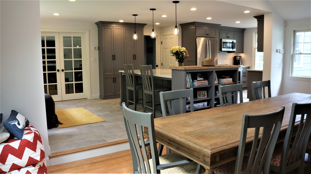 Mid-sized transitional galley porcelain tile and gray floor open concept kitchen photo in Boston with a farmhouse sink, recessed-panel cabinets, quartz countertops, white backsplash, porcelain backsplash, stainless steel appliances, an island and white countertops