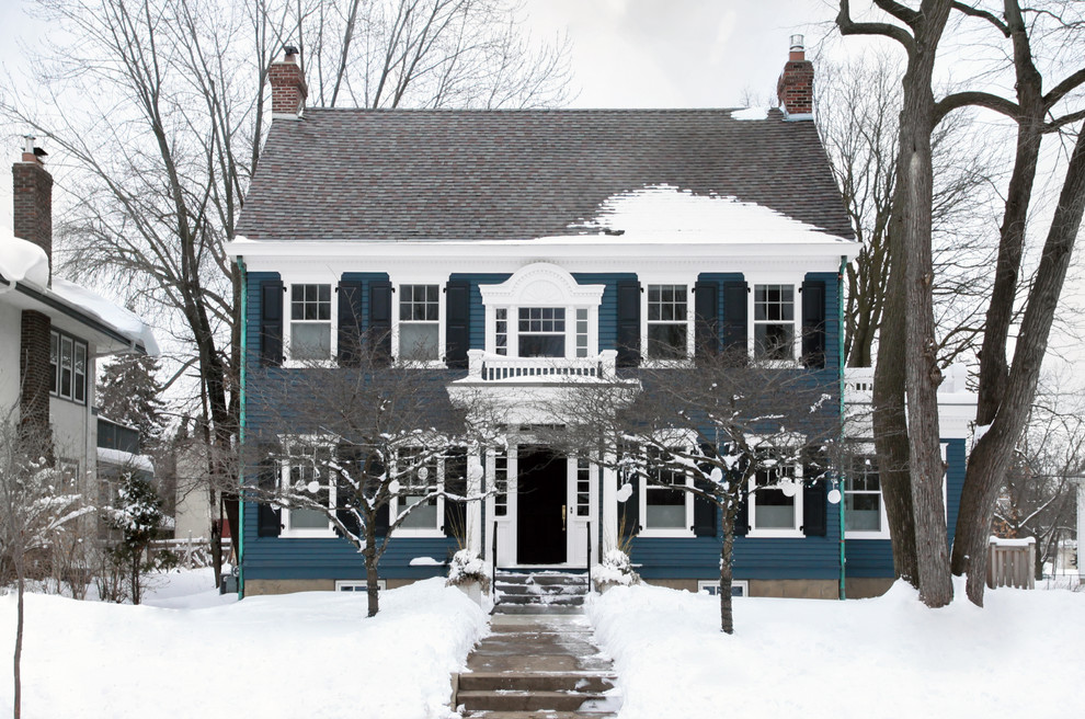 Large traditional two-storey blue house exterior in Minneapolis with a gable roof, a shingle roof and wood siding.