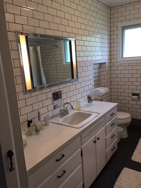 This is an example of a mid-sized traditional master bathroom in Minneapolis with flat-panel cabinets, medium wood cabinets, an alcove tub, a shower/bathtub combo, a two-piece toilet, blue tile, subway tile, white walls, laminate floors, a drop-in sink and laminate benchtops.