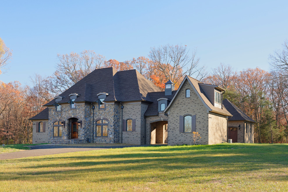 Photo of an expansive country two-storey grey house exterior in DC Metro with stone veneer.