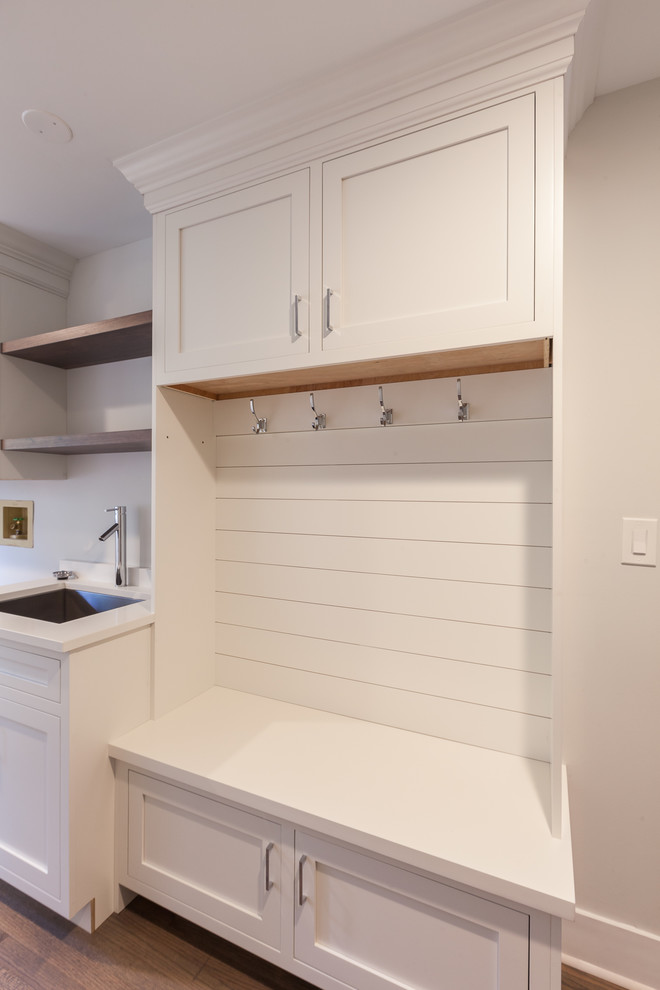 Inspiration for a mid-sized transitional single-wall utility room in Chicago with an undermount sink, shaker cabinets, white cabinets, quartz benchtops, grey walls, medium hardwood floors, a side-by-side washer and dryer and brown floor.