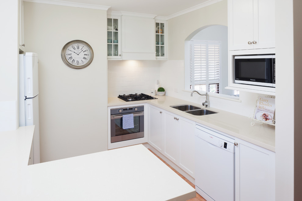 Traditional kitchen in Perth with an undermount sink, shaker cabinets, white cabinets, quartz benchtops, white splashback, ceramic splashback and white benchtop.