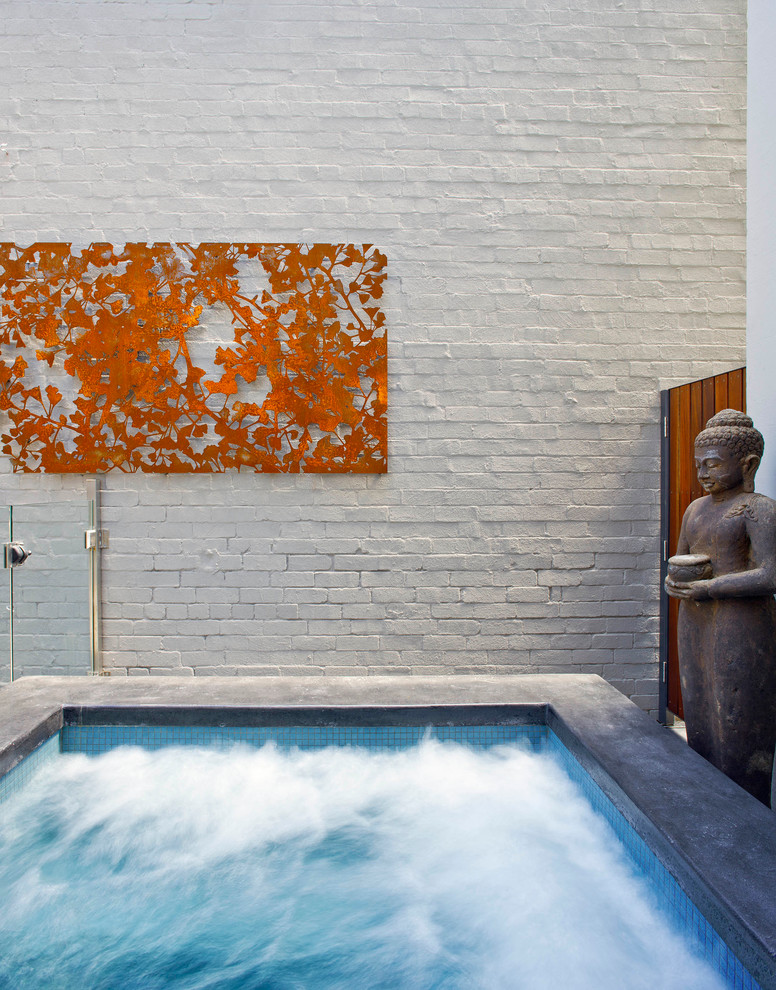 Design ideas for a small asian courtyard custom-shaped pool in Sydney with a hot tub and natural stone pavers.