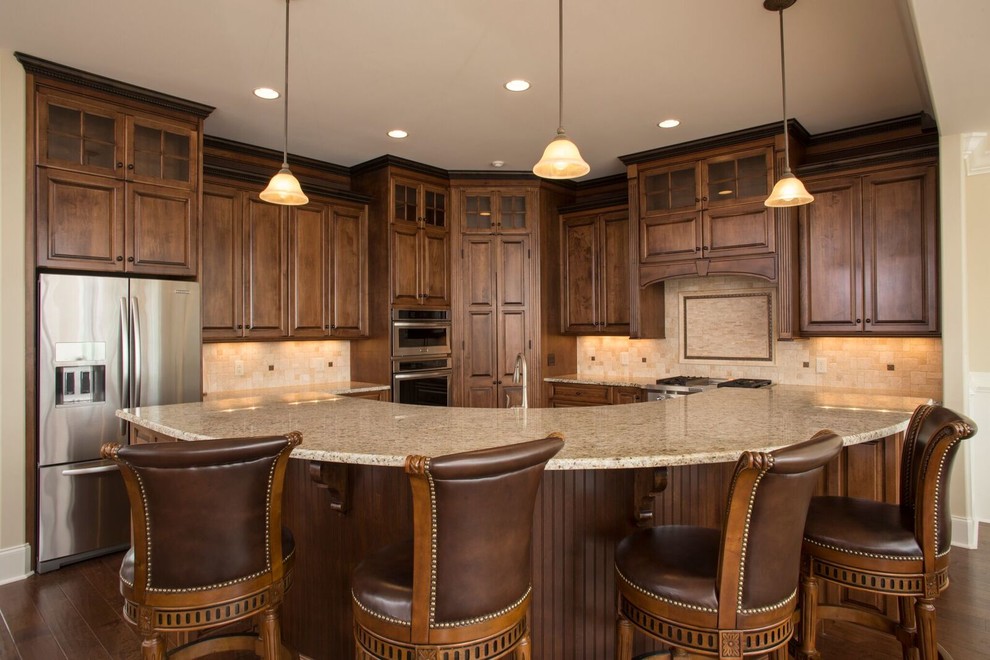 This is an example of a mid-sized traditional l-shaped eat-in kitchen in Other with raised-panel cabinets, dark wood cabinets, granite benchtops, beige splashback, stone tile splashback, stainless steel appliances, dark hardwood floors, with island and brown floor.