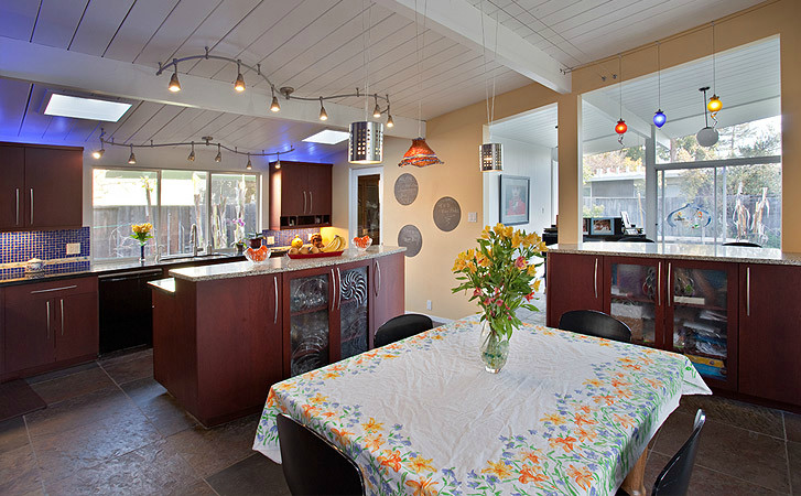 Eat-in kitchen - mid-sized shabby-chic style single-wall limestone floor and brown floor eat-in kitchen idea with a drop-in sink, medium tone wood cabinets, stainless steel appliances, an island, flat-panel cabinets, granite countertops, blue backsplash and mosaic tile backsplash