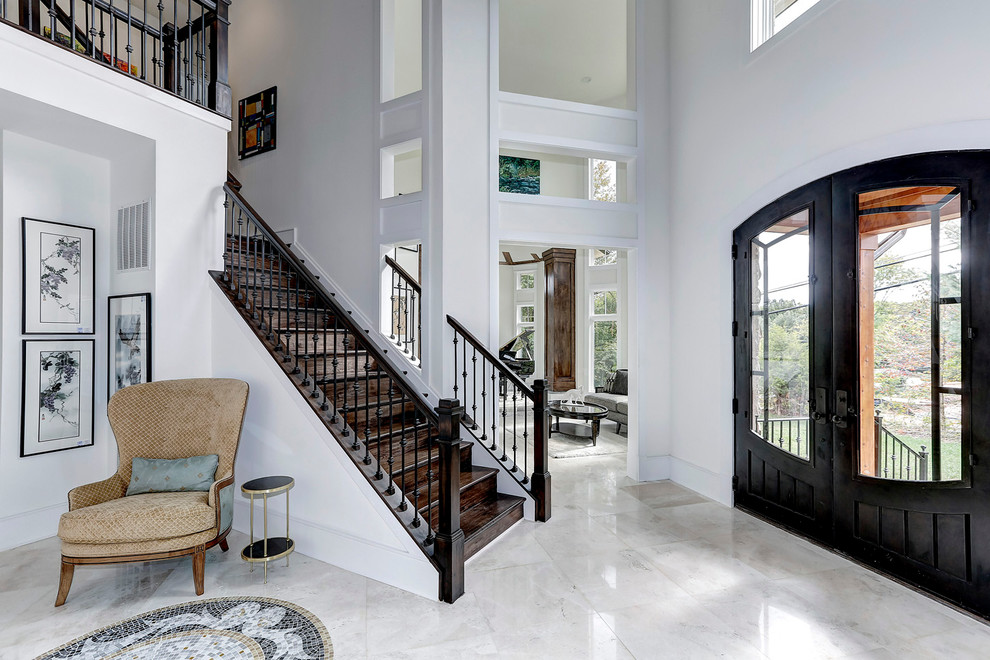 Photo of a large traditional foyer in DC Metro with white walls, a double front door, a black front door and marble floors.