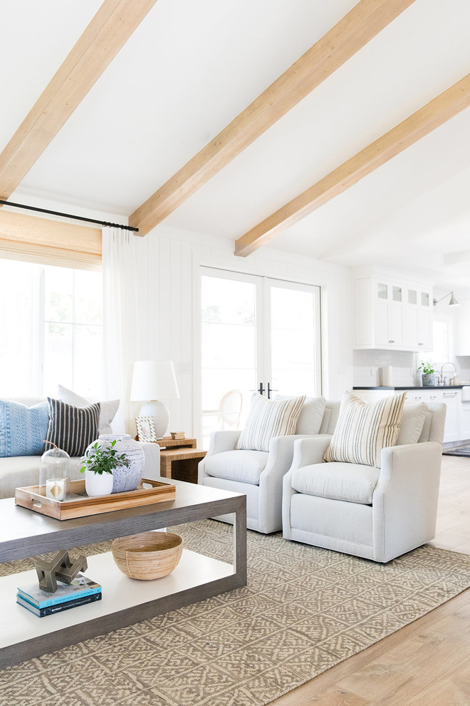 This is an example of a mid-sized beach style open concept living room in Salt Lake City with white walls, light hardwood floors and a two-sided fireplace.