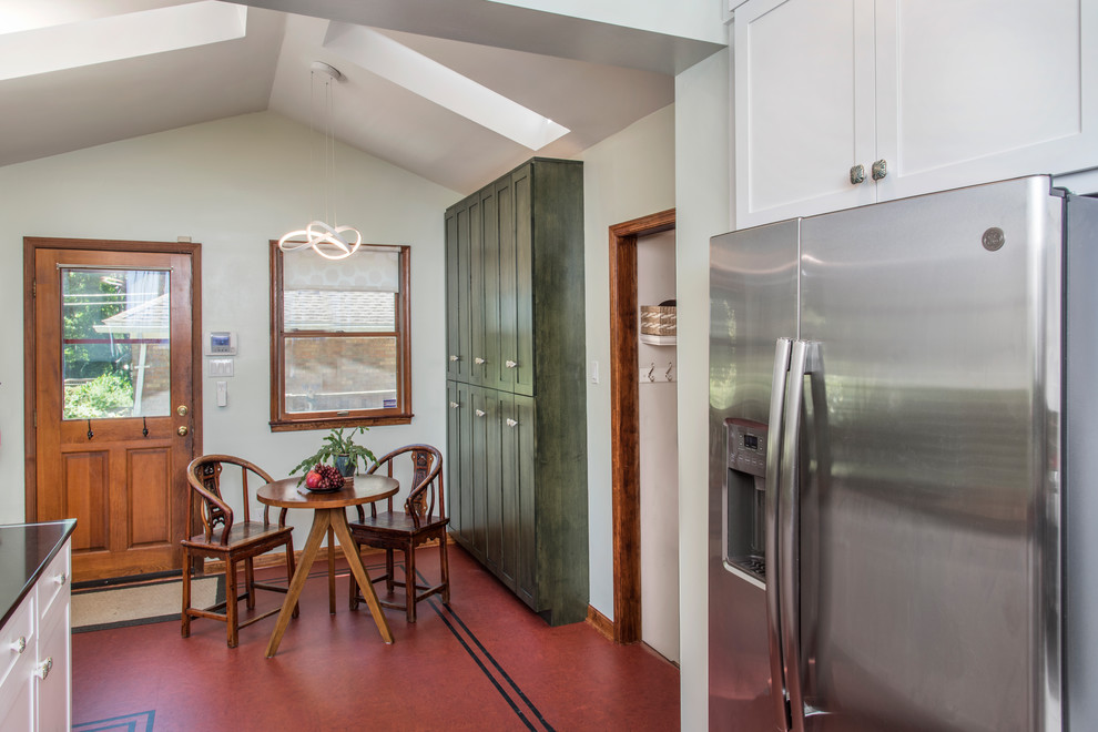 Mid-sized transitional l-shaped linoleum floor and red floor eat-in kitchen photo in Philadelphia with a double-bowl sink, shaker cabinets, white cabinets, quartzite countertops, green backsplash, glass tile backsplash, stainless steel appliances and black countertops