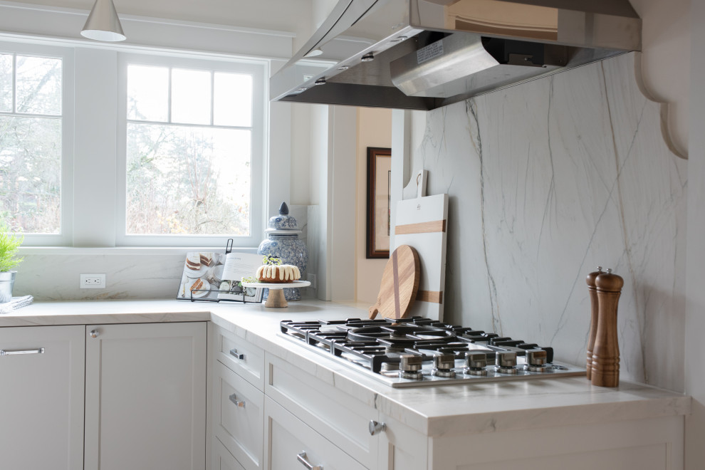 Klassisk inredning av ett avskilt, mellanstort vit vitt u-kök, med en rustik diskho, luckor med infälld panel, vita skåp, bänkskiva i kvartsit, vitt stänkskydd, stänkskydd i sten, rostfria vitvaror, ljust trägolv, en köksö och brunt golv