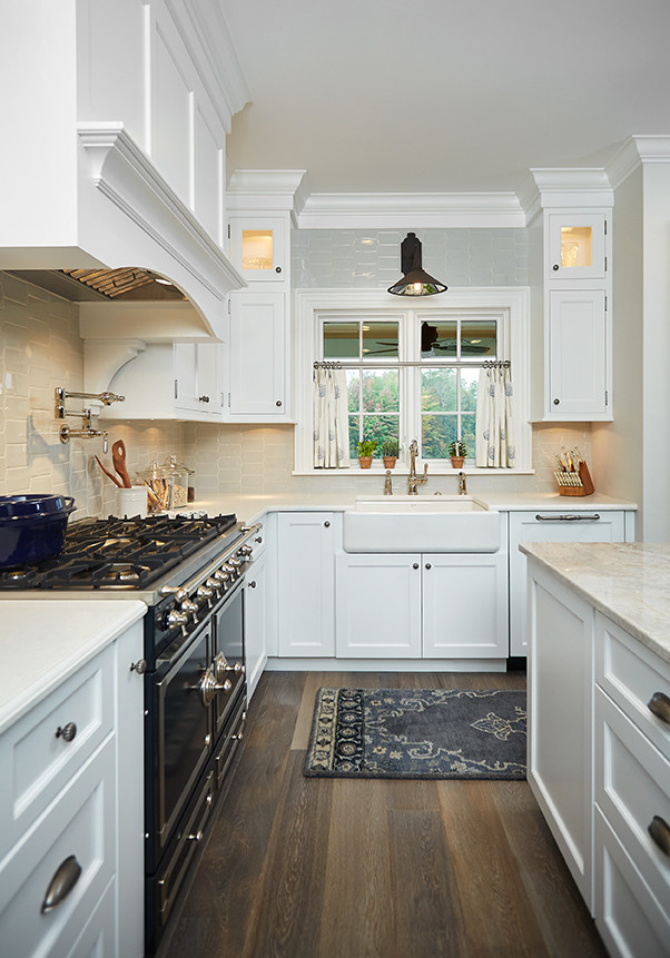 Inspiration for a large traditional l-shaped eat-in kitchen with a farmhouse sink, shaker cabinets, white cabinets, marble benchtops, white splashback, ceramic splashback, panelled appliances, vinyl floors, with island, multi-coloured floor and beige benchtop.