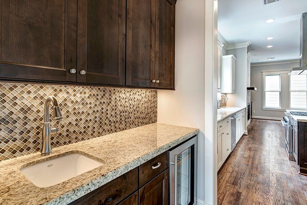 This is an example of a mid-sized transitional l-shaped kitchen pantry in Houston with an undermount sink, shaker cabinets, white cabinets, granite benchtops, brown splashback, subway tile splashback, stainless steel appliances, medium hardwood floors, with island and brown floor.
