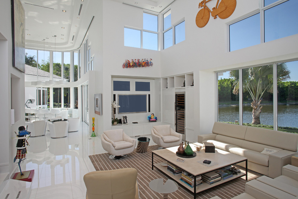 Expansive contemporary open concept family room in Miami with white walls, a wall-mounted tv, a library, marble floors and white floor.