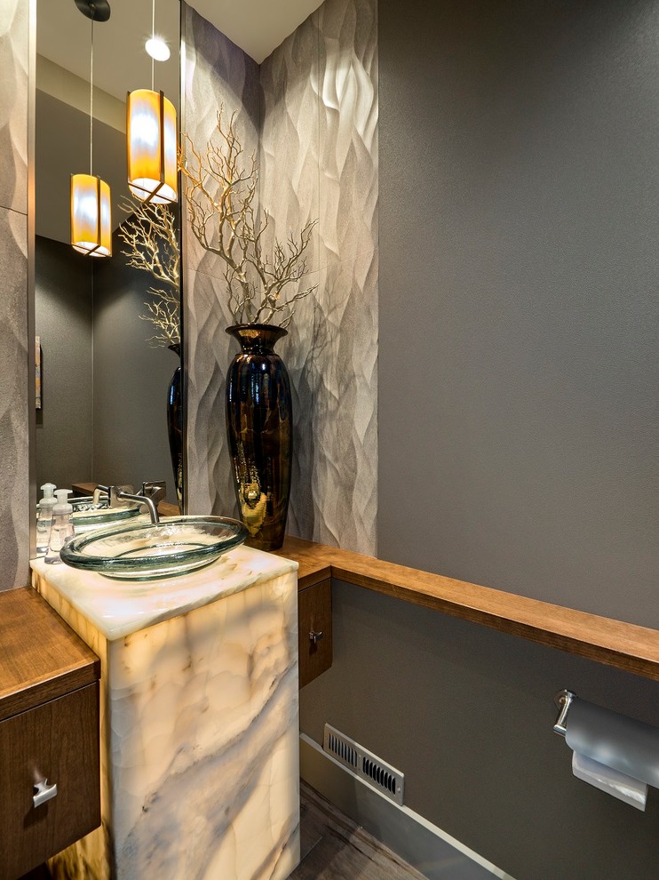 Photo of a contemporary powder room in Denver with flat-panel cabinets, medium wood cabinets, porcelain tile, a vessel sink and onyx benchtops.