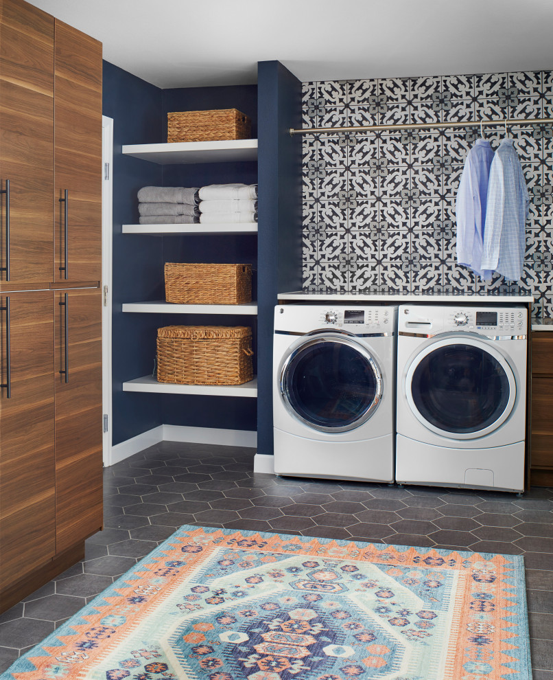 Photo of a large scandinavian galley utility room in Denver with flat-panel cabinets, medium wood cabinets, solid surface benchtops, multi-coloured walls, slate floors, a side-by-side washer and dryer, grey floor and white benchtop.