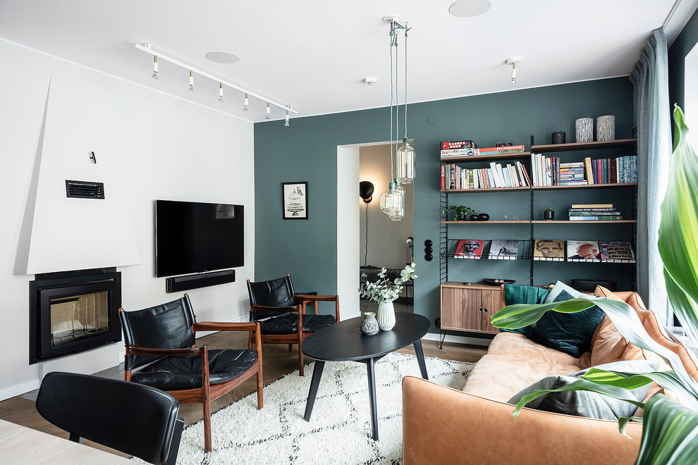 Photo of a large scandinavian open concept living room in Gothenburg with blue walls, dark hardwood floors, a standard fireplace, a plaster fireplace surround, a wall-mounted tv and brown floor.