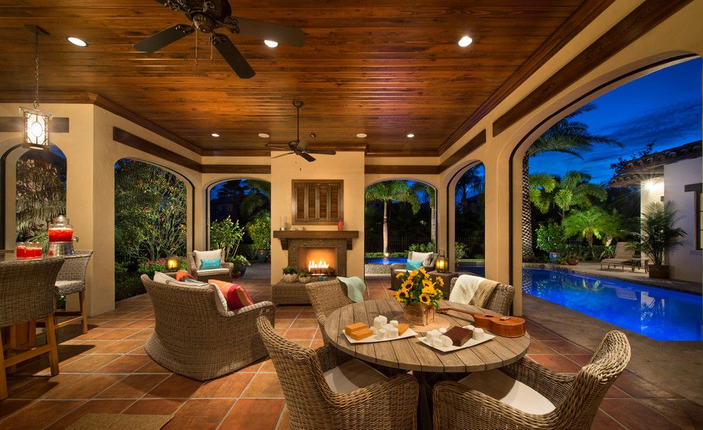 Design ideas for a large mediterranean backyard patio in Orlando with a fire feature, tile and a roof extension.