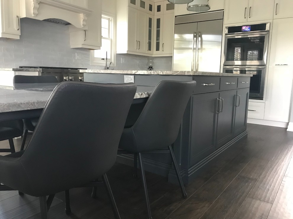 Example of a large transitional l-shaped dark wood floor and brown floor open concept kitchen design in Toronto with recessed-panel cabinets, white backsplash, subway tile backsplash, stainless steel appliances, an island, an undermount sink, beige cabinets, granite countertops and gray countertops