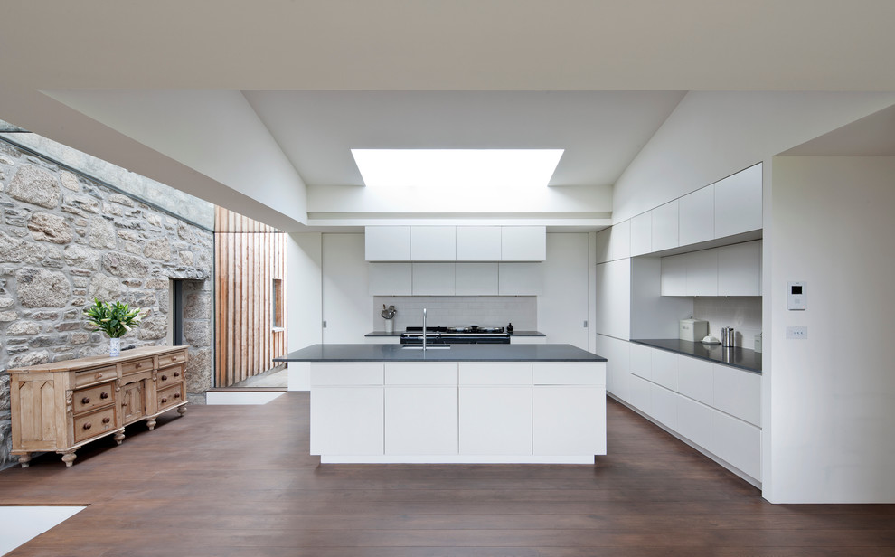 Photo of a contemporary kitchen in Other with an undermount sink, flat-panel cabinets, white cabinets, white splashback, subway tile splashback, medium hardwood floors and with island.