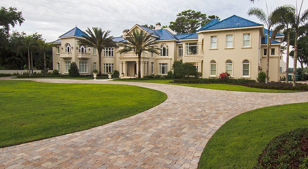 This is an example of an expansive mediterranean two-storey stucco beige exterior in Tampa with a hip roof.