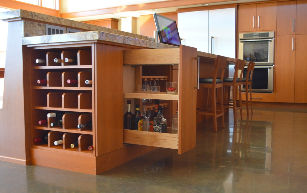 Example of a large concrete floor kitchen design with flat-panel cabinets, medium tone wood cabinets, quartzite countertops, stainless steel appliances and an island