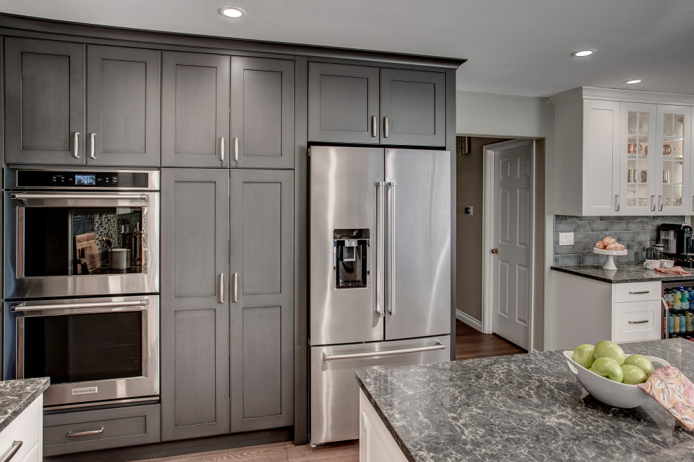 Example of a mid-sized transitional l-shaped medium tone wood floor and brown floor eat-in kitchen design in Seattle with a double-bowl sink, shaker cabinets, gray cabinets, quartz countertops, gray backsplash, ceramic backsplash, stainless steel appliances, two islands and gray countertops