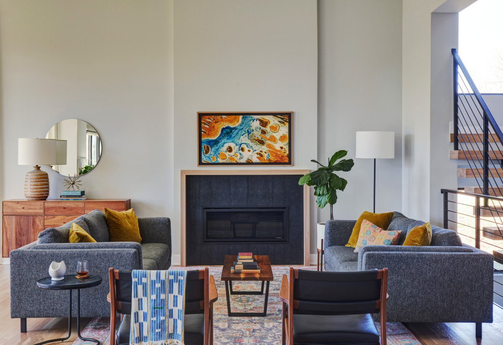 Idée de décoration pour une salle de séjour vintage avec un mur gris, parquet clair, une cheminée standard, un manteau de cheminée en métal et un téléviseur fixé au mur.