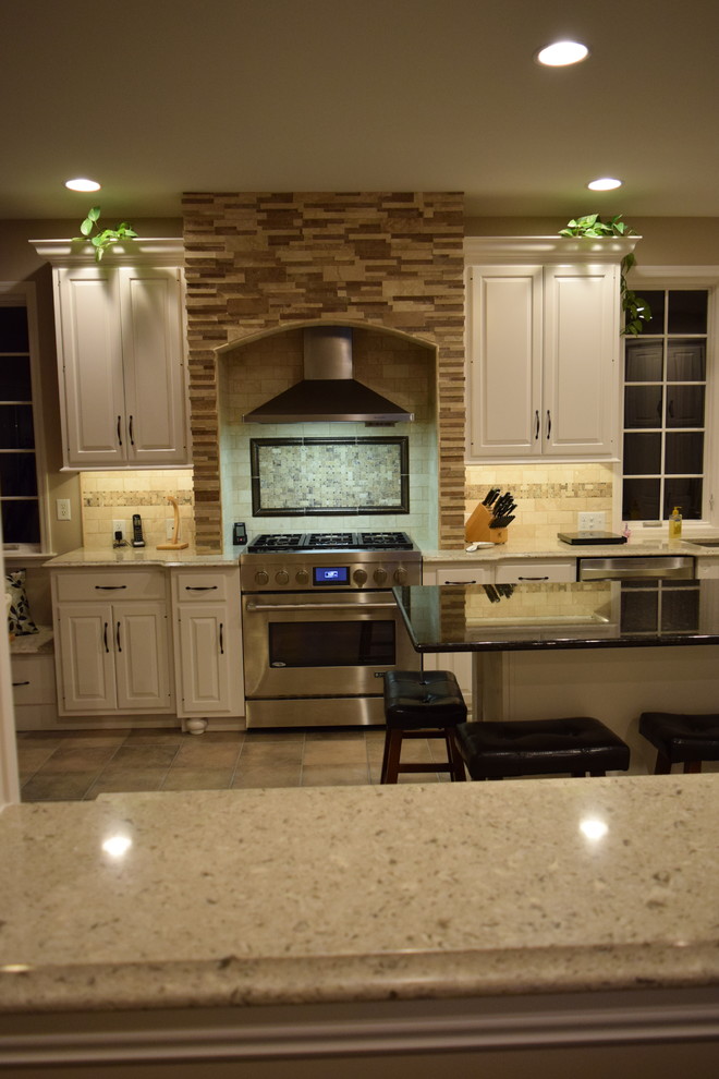 Kitchen - transitional ceramic tile kitchen idea with an undermount sink, raised-panel cabinets, quartz countertops, beige backsplash, ceramic backsplash, stainless steel appliances and an island