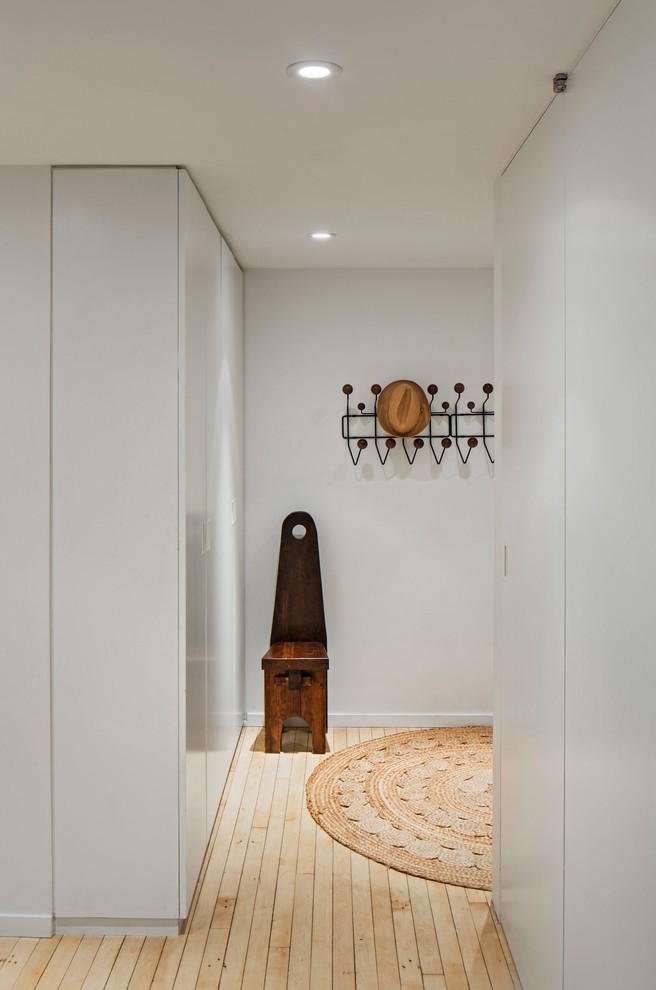 Design ideas for a small modern entryway in New York with white walls, light hardwood floors and beige floor.