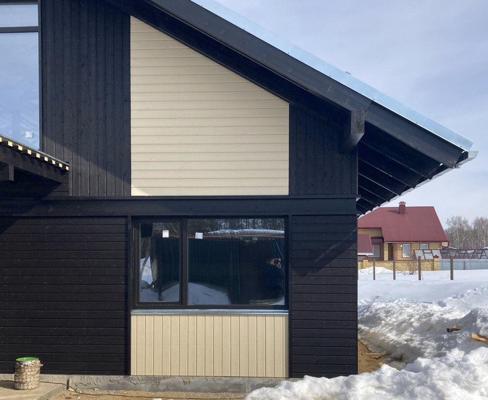 Imagen de fachada de casa negra y gris escandinava de tamaño medio de una planta con revestimiento de madera, tejado a dos aguas, tejado de metal y tablilla
