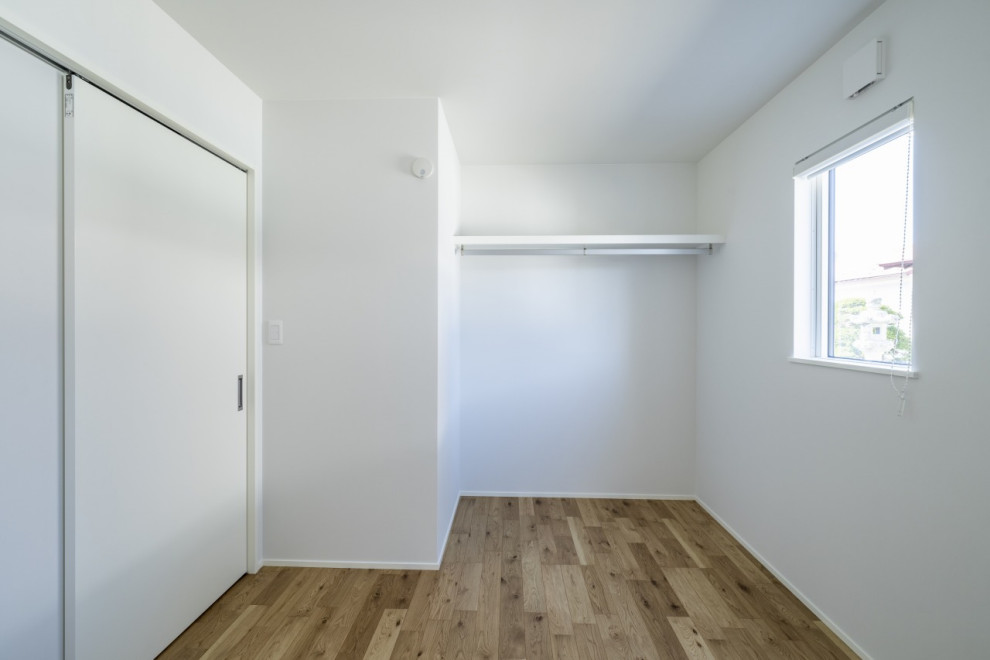 Photo of a mid-sized modern gender-neutral kids' room in Other with white walls, light hardwood floors, brown floor, wallpaper and wallpaper.