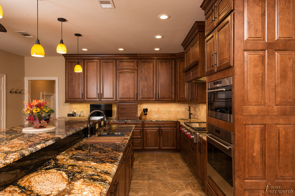 Eat-in kitchen - mid-sized traditional galley travertine floor eat-in kitchen idea in Dallas with an undermount sink, raised-panel cabinets, dark wood cabinets, granite countertops, beige backsplash, ceramic backsplash, stainless steel appliances and an island