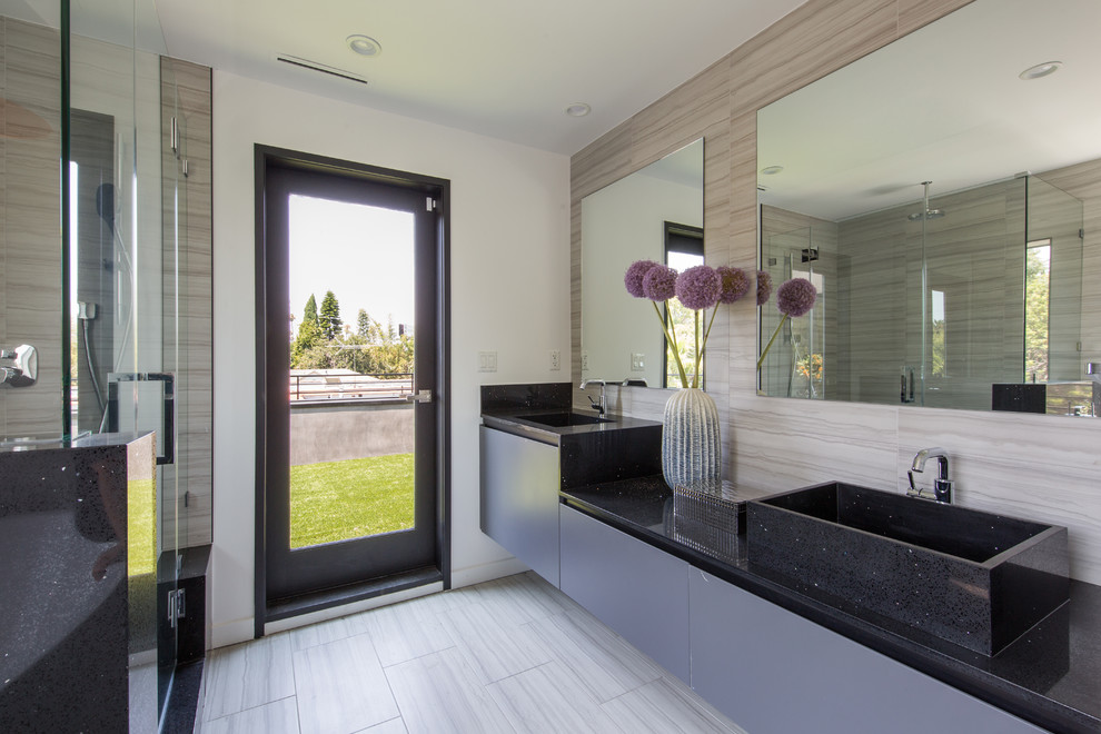 Photo of a large contemporary master bathroom in Los Angeles with flat-panel cabinets, grey cabinets, a freestanding tub, a corner shower, beige tile, porcelain tile, beige walls, porcelain floors, a vessel sink, granite benchtops, grey floor and a hinged shower door.