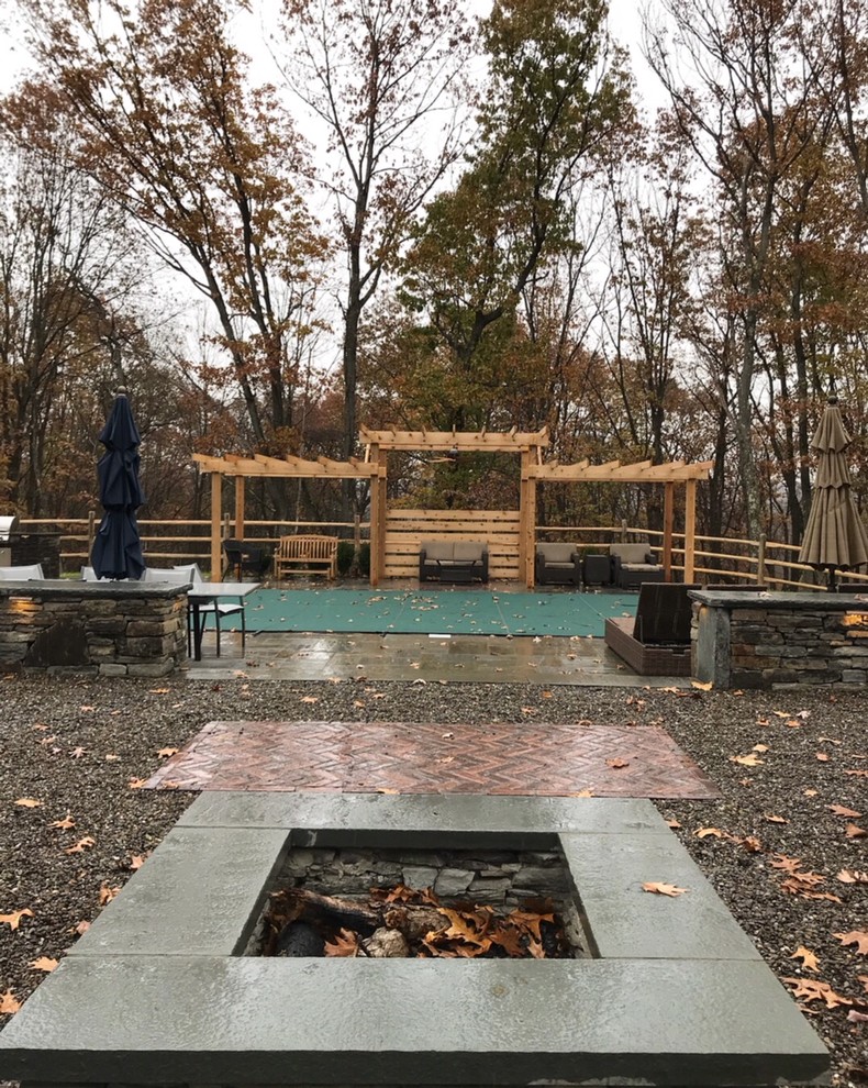 Design ideas for a contemporary backyard patio in New York with a fire feature, natural stone pavers and a pergola.