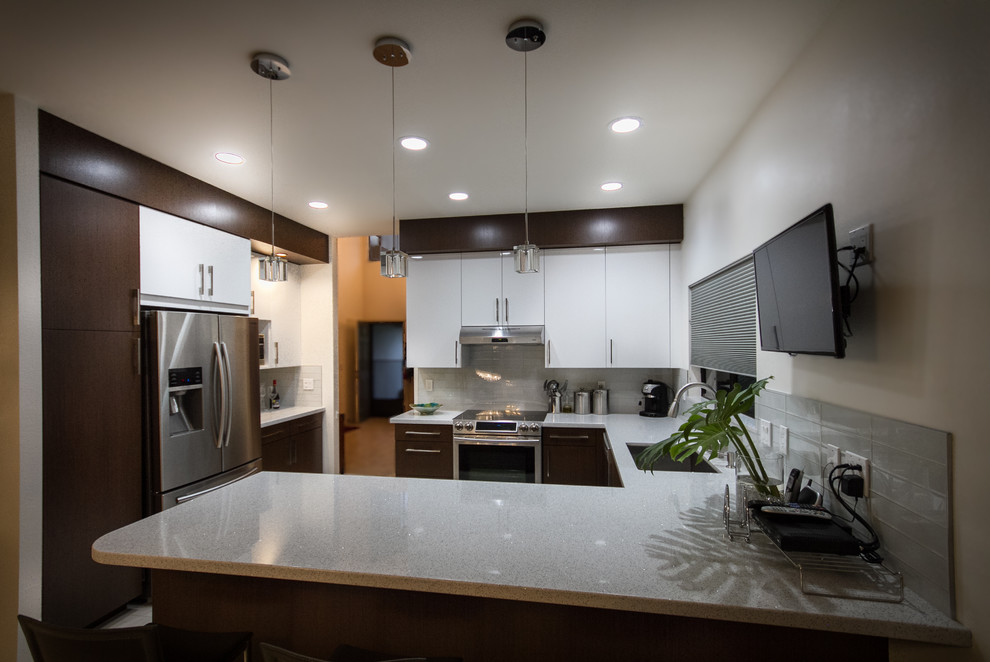 Design ideas for a mid-sized modern u-shaped kitchen in Hawaii with an undermount sink, flat-panel cabinets, white cabinets, quartz benchtops, white splashback, glass tile splashback, stainless steel appliances, ceramic floors and a peninsula.