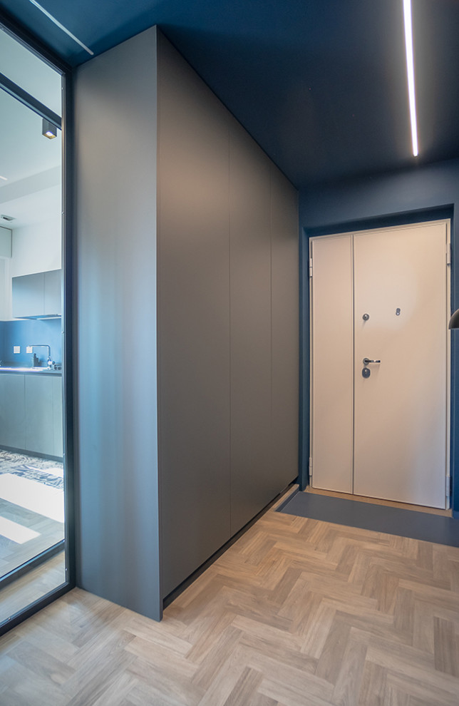 Foto de distribuidor actual de tamaño medio con paredes azules, suelo de madera clara y suelo gris