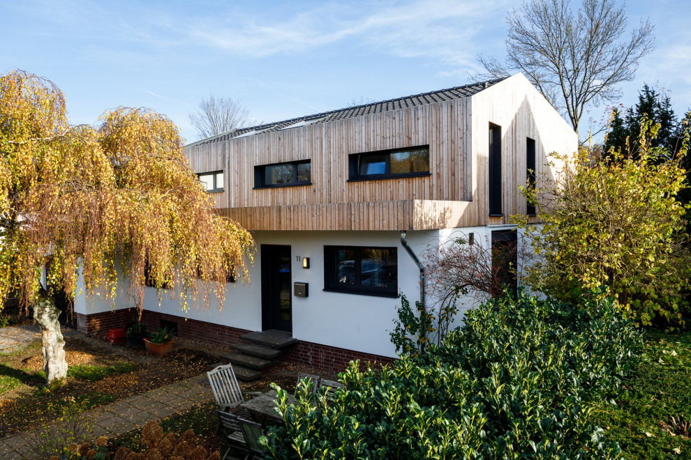 Imagen de fachada de casa gris moderna de tamaño medio de dos plantas con revestimientos combinados, tejado de un solo tendido, tejado de teja de barro y tablilla