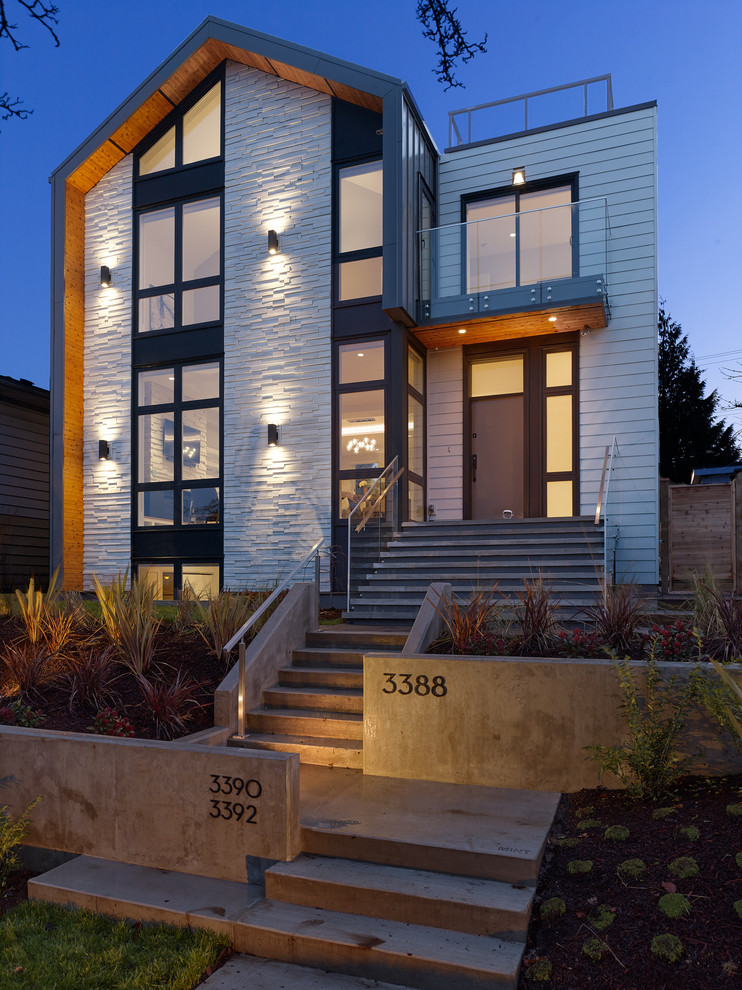 Mid-sized modern three-storey black house exterior in Vancouver with metal siding, a gable roof and a metal roof.