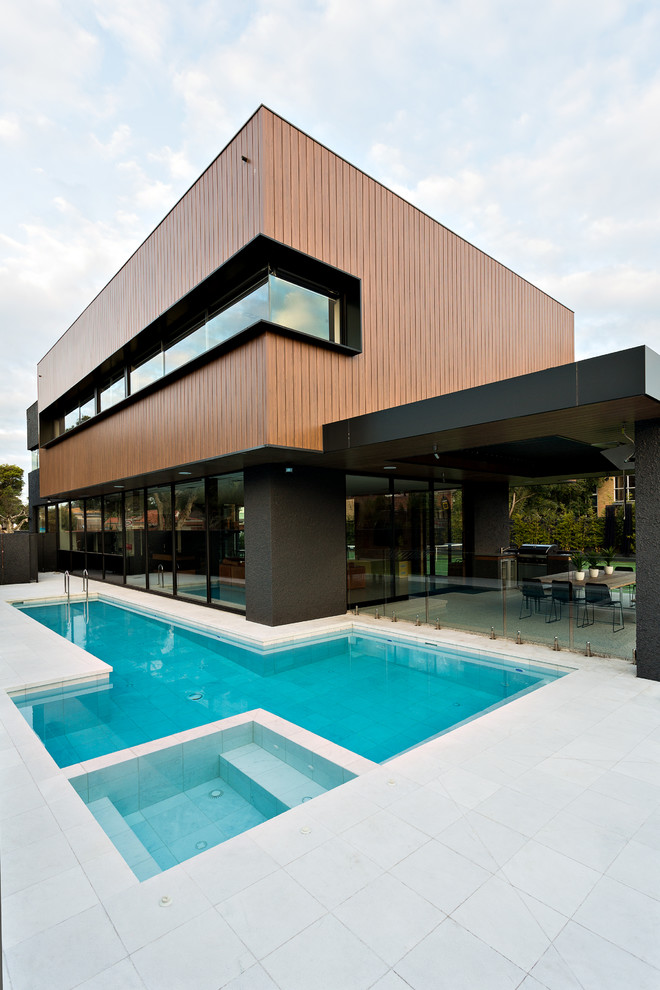 Large contemporary two-storey black exterior in Melbourne with mixed siding and a flat roof.