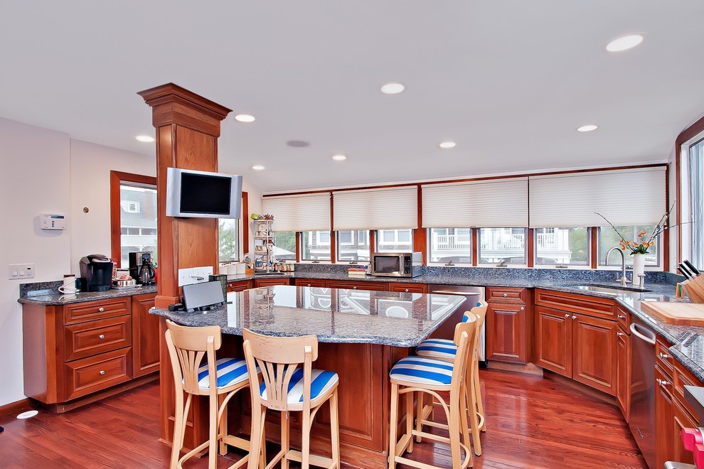 Photo of a large beach style u-shaped eat-in kitchen in New York with a double-bowl sink, medium wood cabinets, granite benchtops, stainless steel appliances, medium hardwood floors and with island.