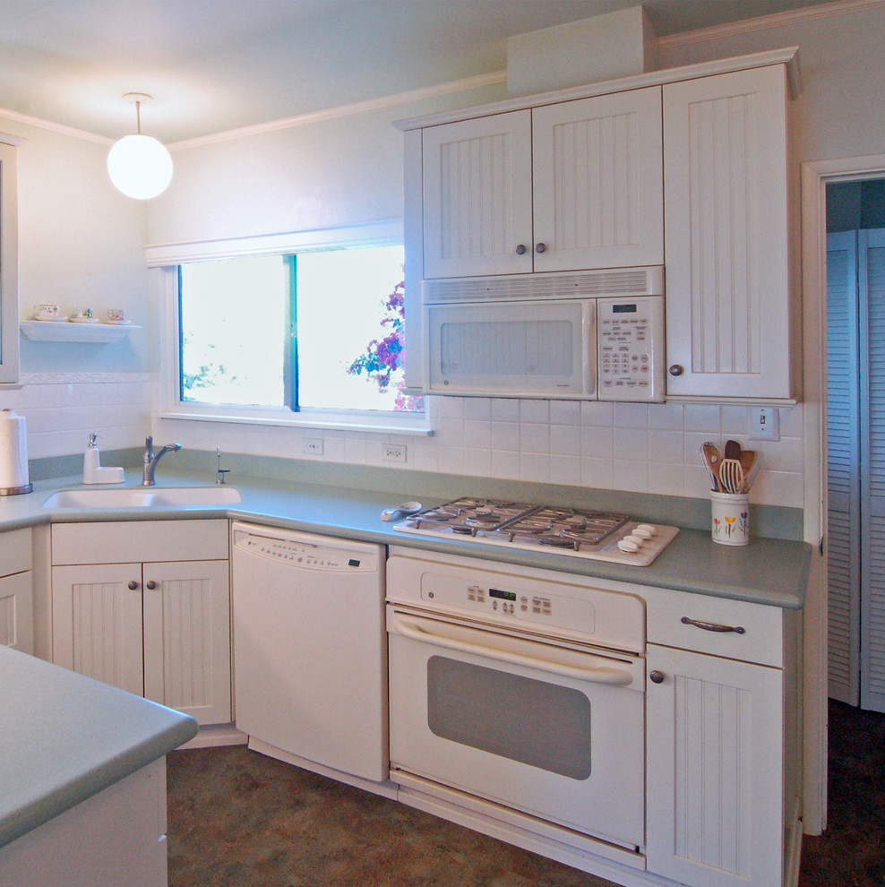 サンルイスオビスポにある小さなカントリー風のおしゃれなキッチン (一体型シンク、インセット扉のキャビネット、白いキャビネット、人工大理石カウンター、白いキッチンパネル、ガラスタイルのキッチンパネル、白い調理設備、リノリウムの床) の写真