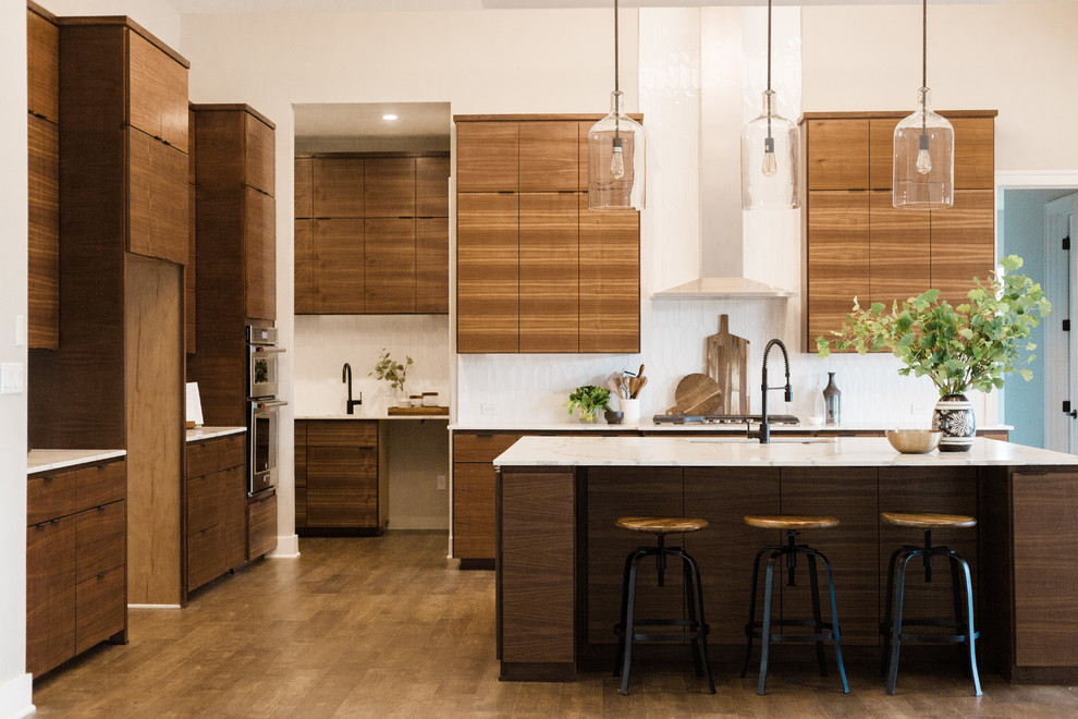 Inspiration for a mid-sized modern l-shaped eat-in kitchen in Austin with an undermount sink, flat-panel cabinets, medium wood cabinets, quartz benchtops, white splashback, stainless steel appliances, dark hardwood floors, with island, brown floor and white benchtop.