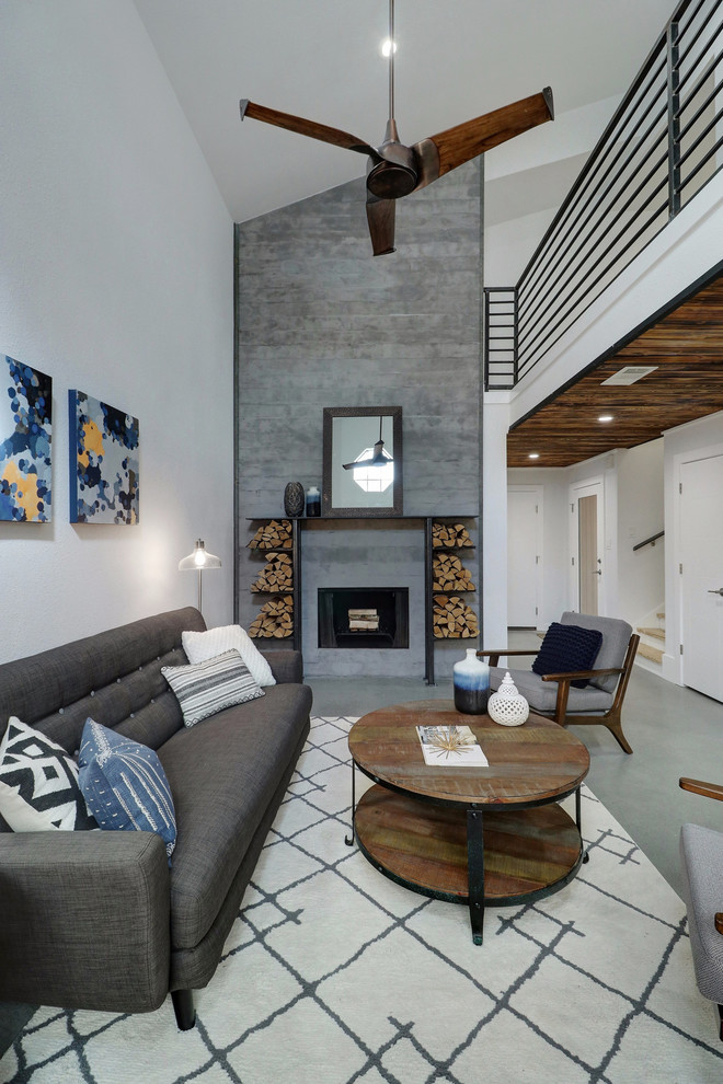 This is an example of a contemporary open concept living room in Austin with white walls, a standard fireplace, grey floor and concrete floors.