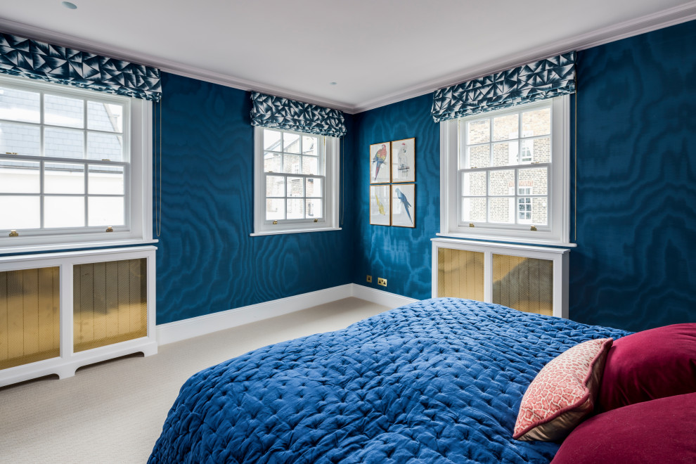 Photo of a large tropical guest bedroom in London with blue walls, carpet, beige floor and wallpaper.