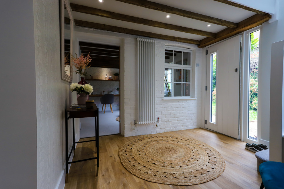 Small contemporary hallway in Surrey with white walls and light hardwood floors.