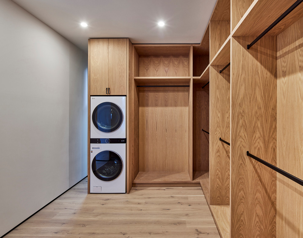 Inspiration for a large modern gender-neutral light wood floor and beige floor walk-in closet remodel in Los Angeles with flat-panel cabinets and light wood cabinets
