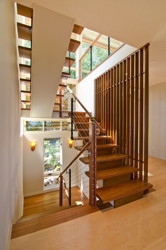 Mid-sized modern wood u-shaped staircase in Portland with cable railing and wood risers.