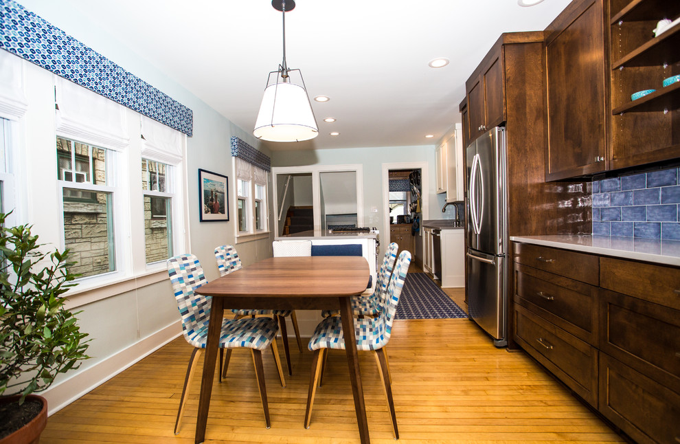 Example of a mid-sized transitional galley light wood floor enclosed kitchen design in Milwaukee with an undermount sink, shaker cabinets, medium tone wood cabinets, quartz countertops, blue backsplash, ceramic backsplash, stainless steel appliances and an island